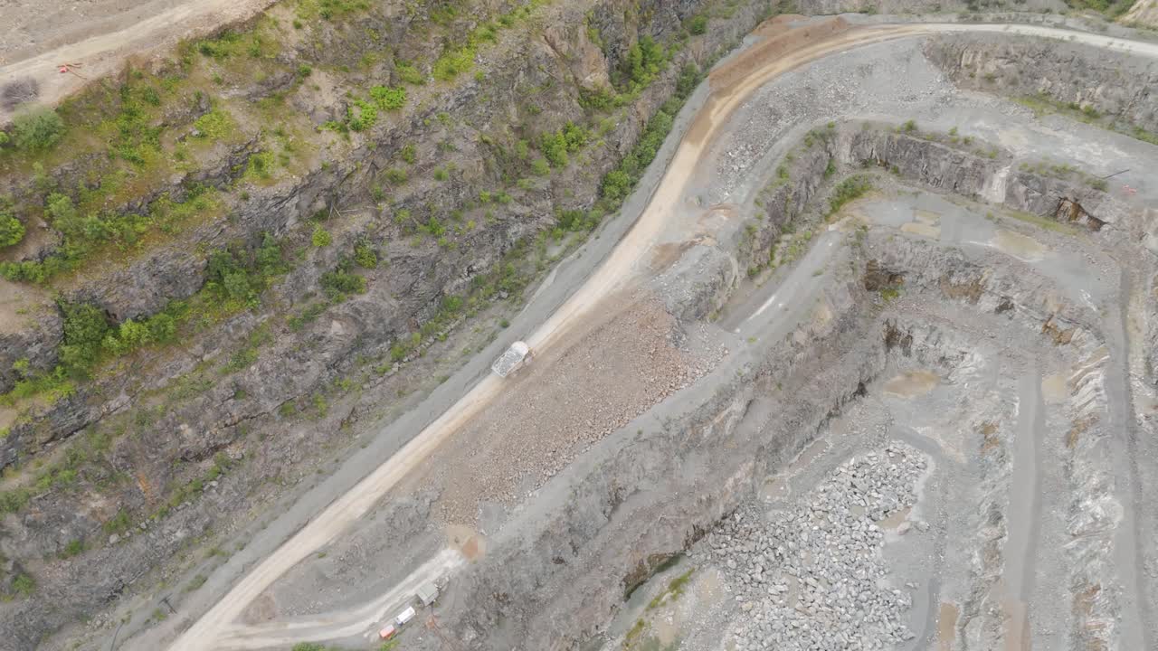 Drone view of large industrial lorry hauling freshly mined aggregate from the quarry floor, illustrating the ongoing mining operations