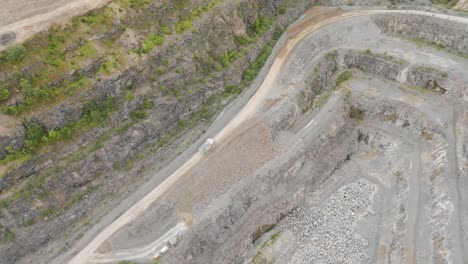 drone view of large industrial lorry hauling freshly mined aggregate from the quarry floor, illustrating the ongoing mining operations