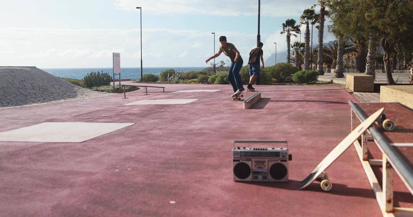 Two Young Men Skateboarding at an Outdoor Skatepark by the Ocean