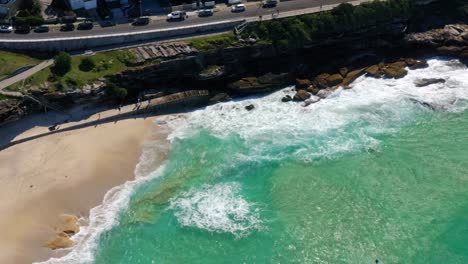 olas rompiendo en la costa arenosa con la carretera costera en la playa de bondi durante la pandemia de covid19 en sydney, nueva gales del sur, australia