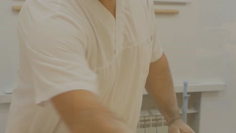 a turkish man pastry chef works with baklava dough. the baker cleans the rolling pin with sandpaper and rolls the dough layers onto the rolling pin. baklava cooking process