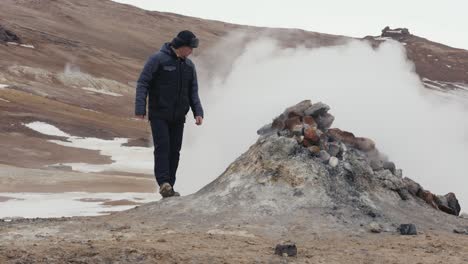 Man-go-by-and-look-at-rocky-active-steam-vent-push-out-vapor,-Iceland