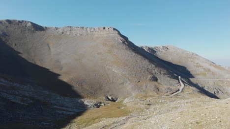 video de drones de picos montañosos monte olimpo grecia en la mañana en un día soleado, camino de tierra en la distancia