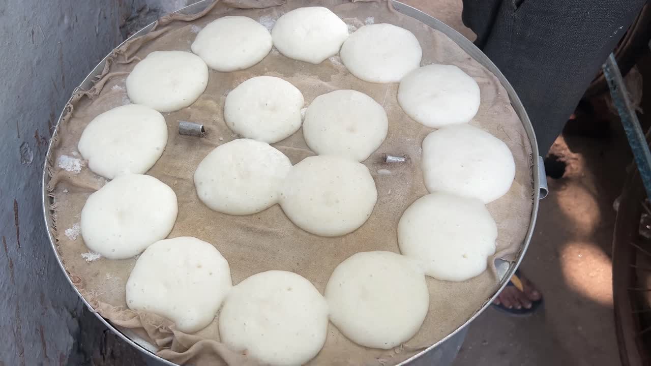 idlis en la fabricación de contenedores de acero en un dhaba junto a la carretera en la india.