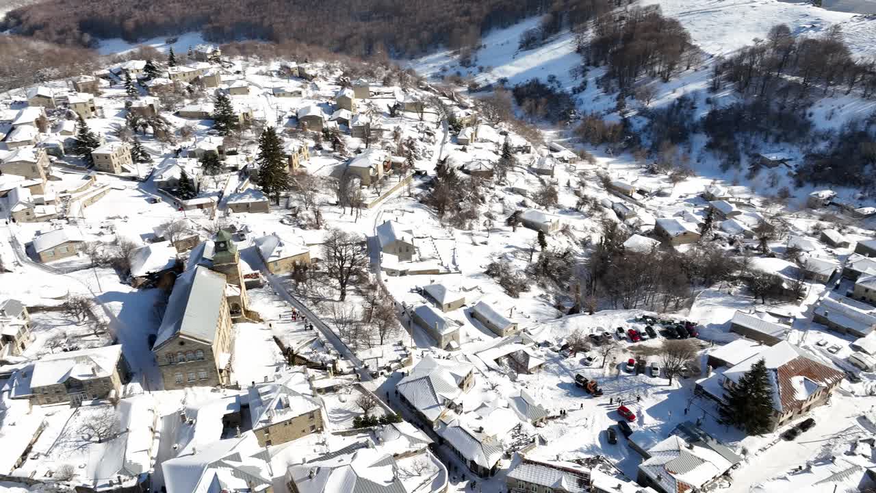 Snow-covered rooftops and winding streets of Nymfaio village nestled in the mountains during winter. Greece