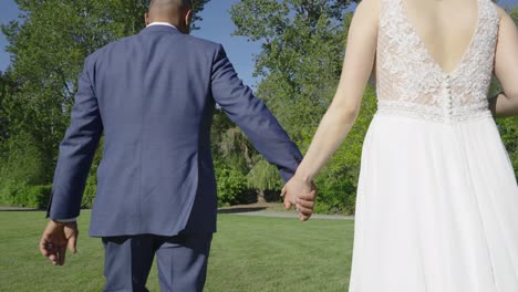 Groom-and-bride-walking-hand-in-hand-on-a-farm-on-their-wedding-day