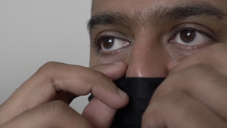 adult uk asian male putting on balaclava face mask indoors