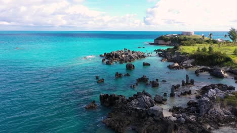 Aerial-view-of-sharp-pointy-rocks-in-turquoise-water-by-tropical-island