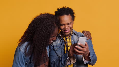 African-american-young-couple-having-fun-together-with-photos-on-smartphone