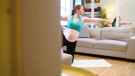 Mujer-Embarazada-Practicando-Yoga-En-La-Sala-De-Estar