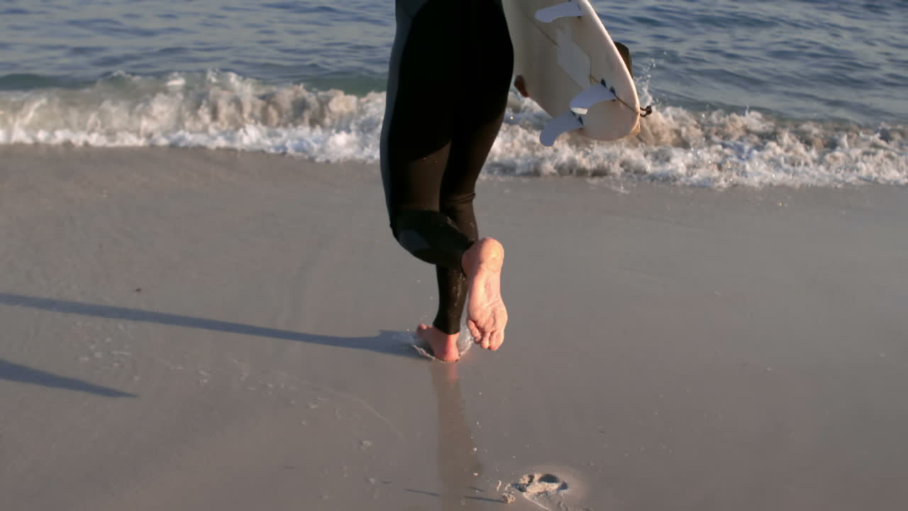 서프 보드를 들고 바다로 달리는 남자