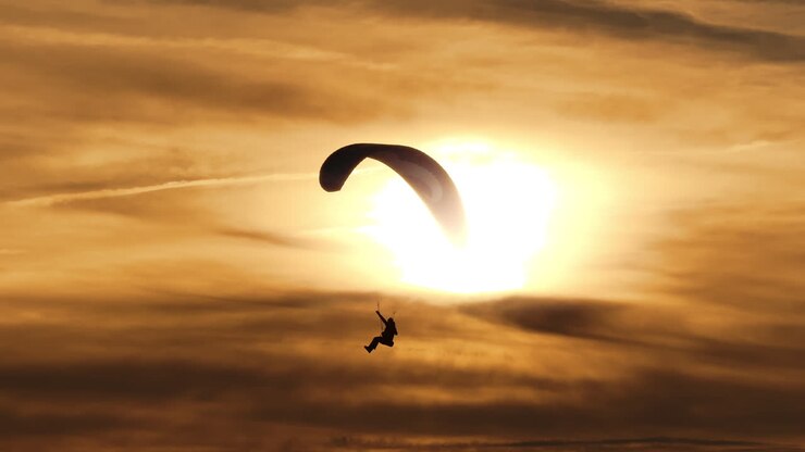 Paragliding over mountains at sunset