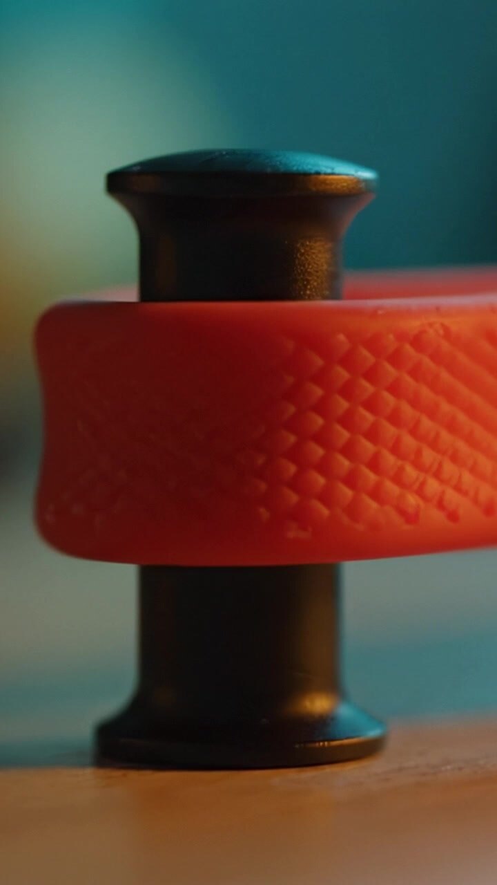 Close-up of a black and orange object showcasing intricate texture and design, set against a blurred colorful background with a focus on structure and detail.
