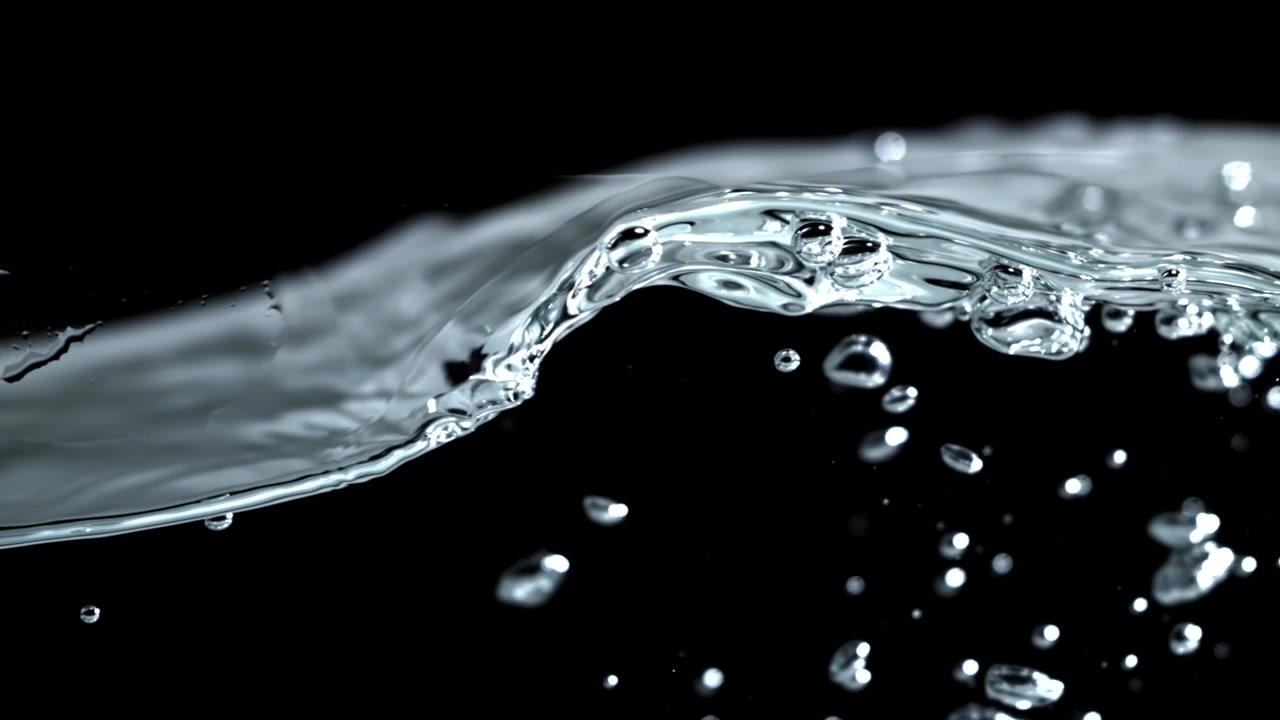Primo piano di una superficie d'acqua limpida con increspature e bolle su sfondo nero