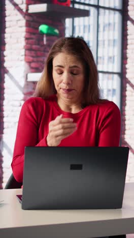 vertical video tired woman sits at her desk staring at laptop screen and yawning in her loft