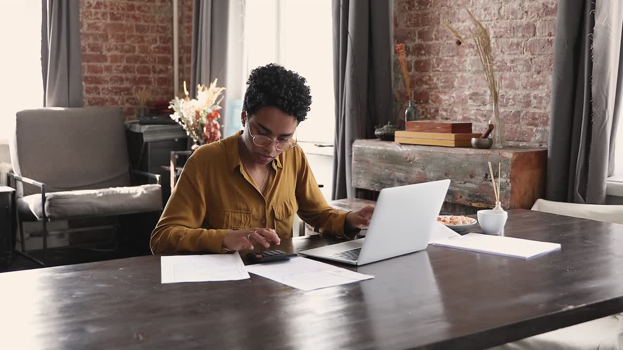 African female sit at desk with laptop do accountancy job