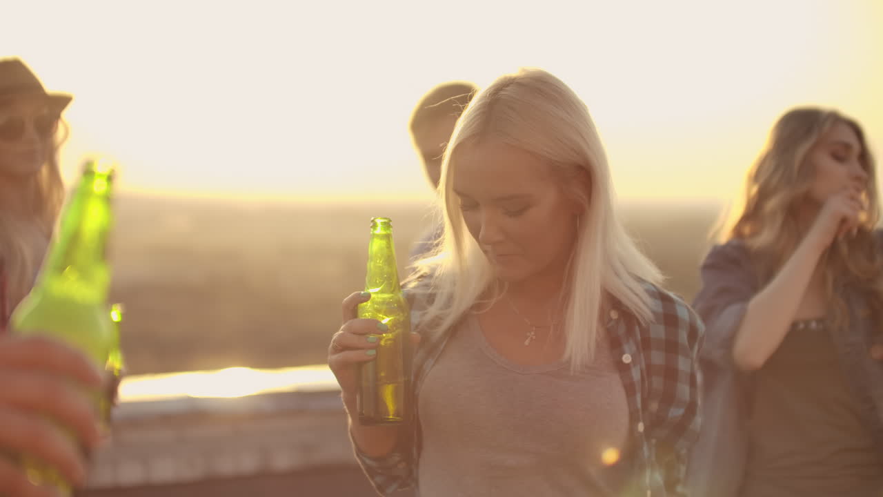 Young girl drinks beer and moves in dance with friends. She enjoys moments and her eyes closed