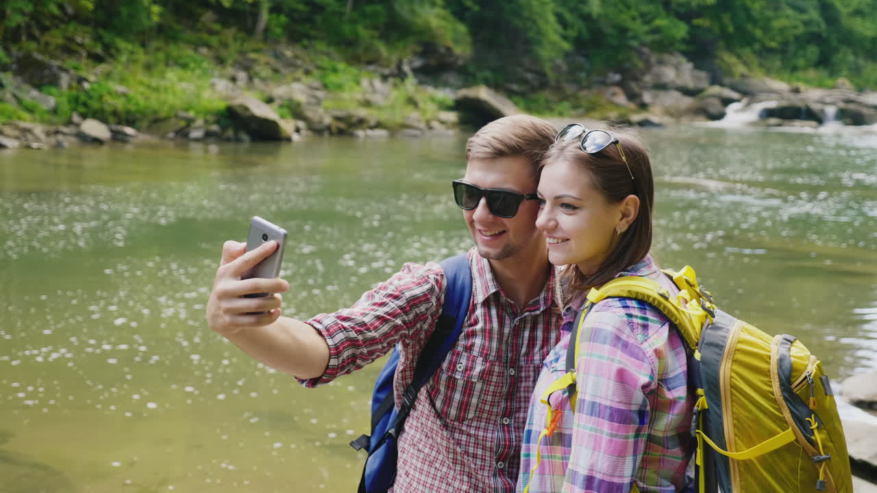 un hombre con una novia es fotografiado contra el fondo de un río de montaña