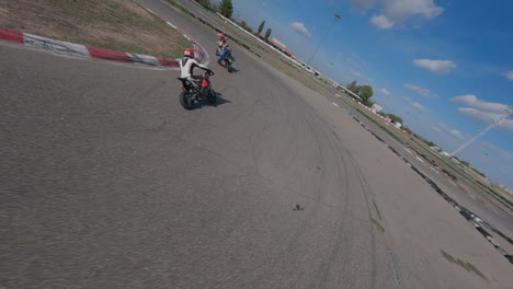 dynamic fpv drone pursuit through motorcycle riders on racetrack lap corners, aerial view