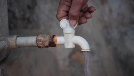 Den-Wasserhahn-Eines-Indischen-Dorfes-Mit-Der-Hand-Eines-Mannes-Zudrehen