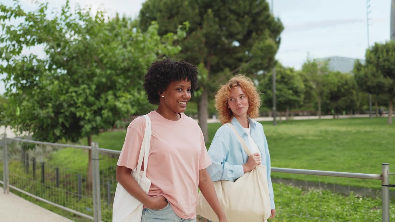 Duas jovens felizes caminhando e conversando em um parque verde