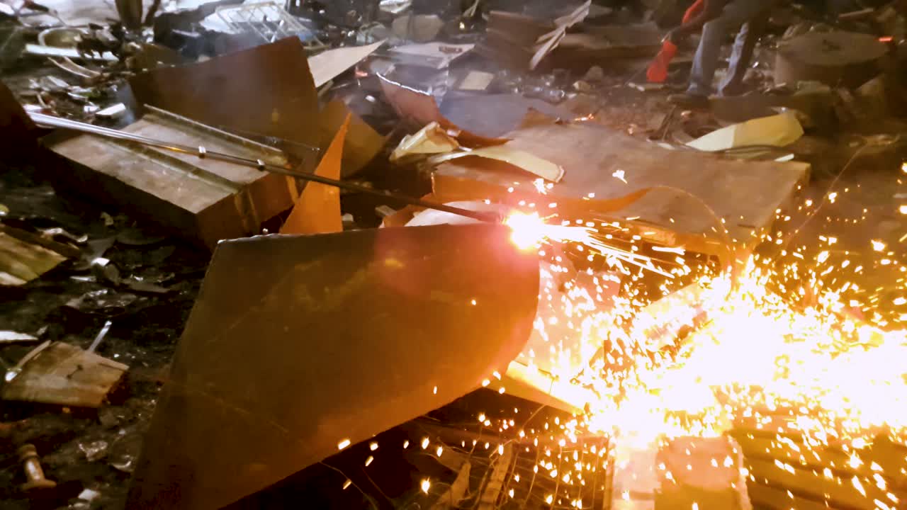 Close up of gas cutter, cutting metal scrap at iron rods construction factory. Slow motion.