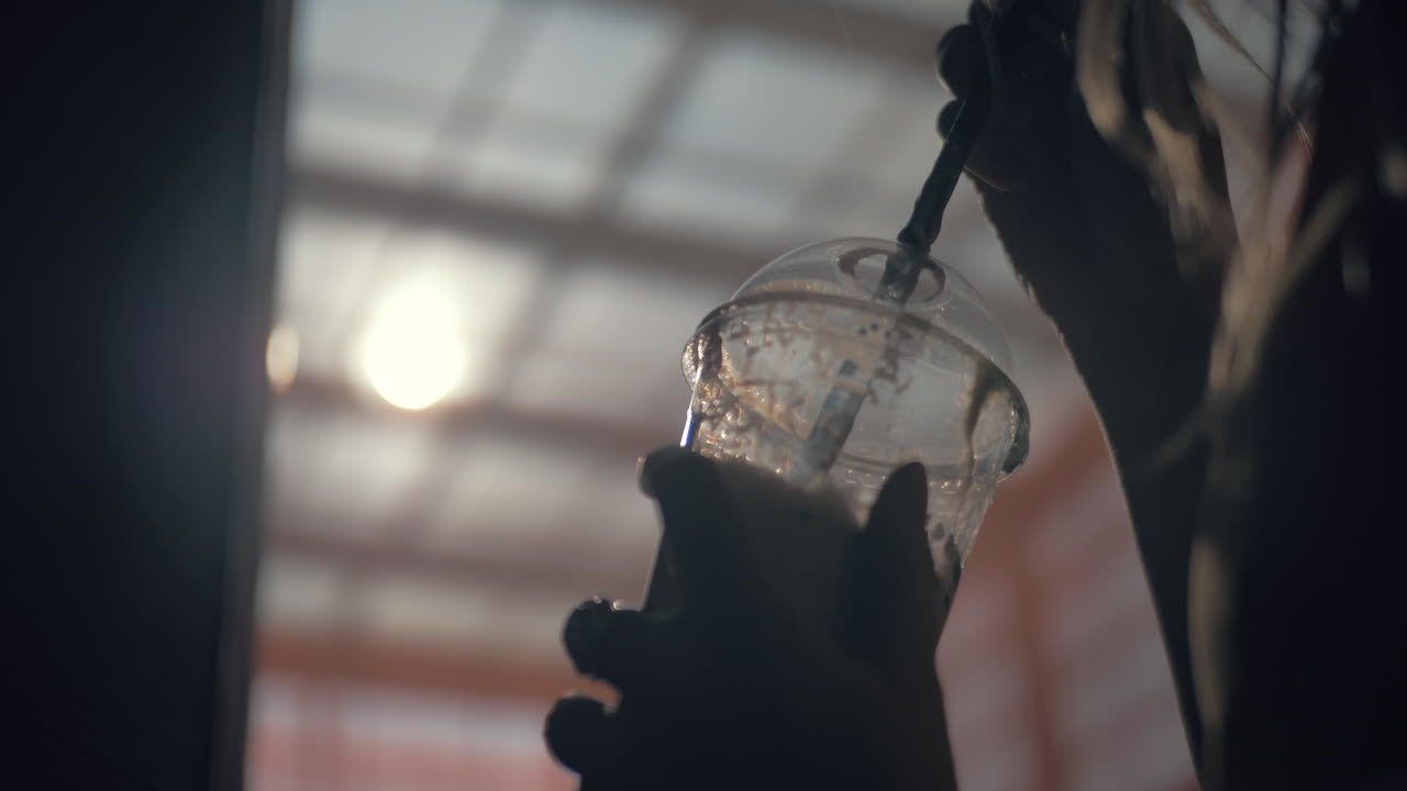 A plastic cup with a straw in females hands