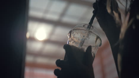 a plastic cup with a straw in females hands