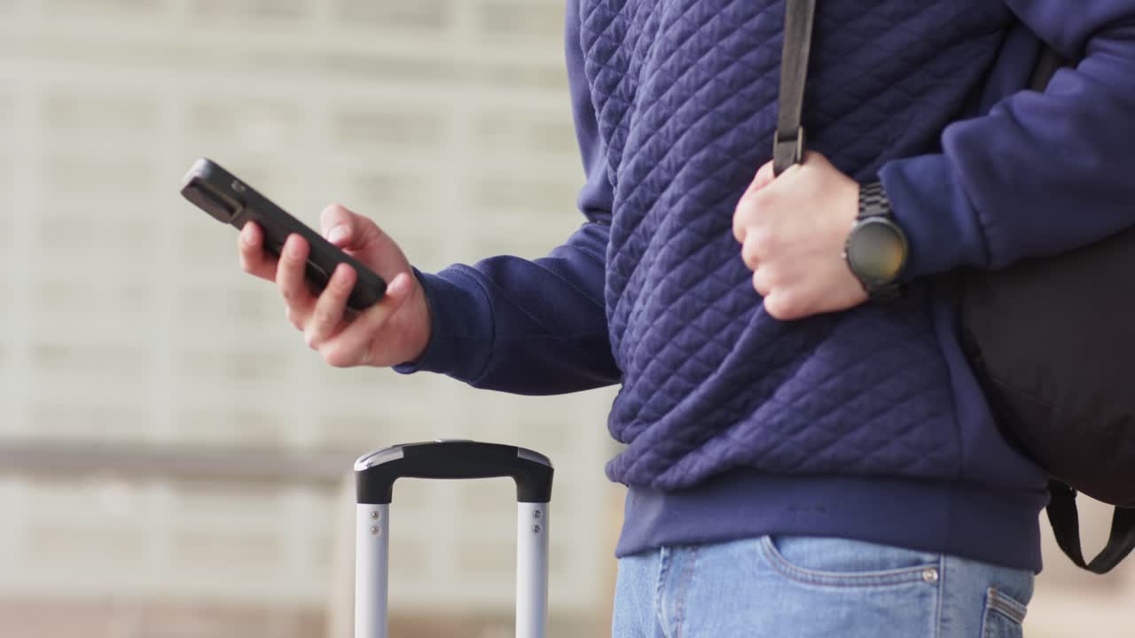 Dopo aver sentito la notifica, l'uomo afferra la valigia ed estrae lo smartphone dalla borsa al centro di transito