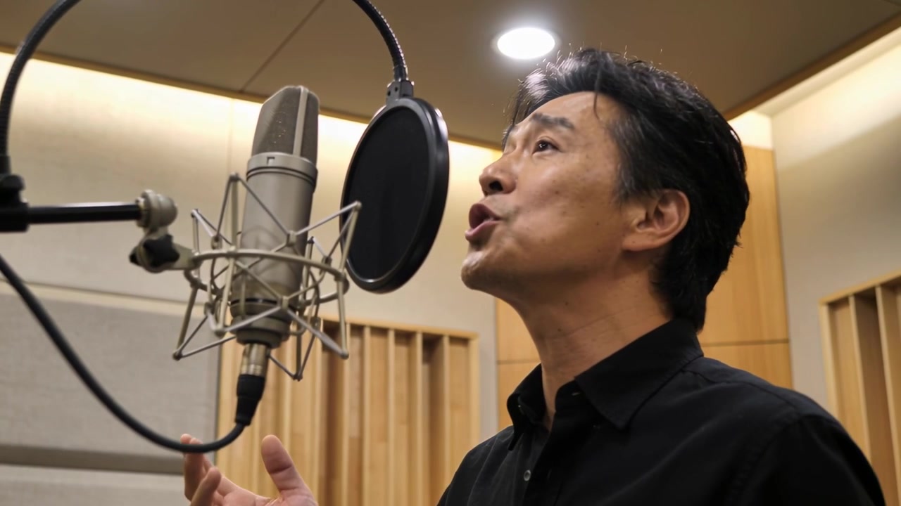Cantante in camicia nera che regola il filtro anti-pop del microfono mentre canta in studio per una sessione.