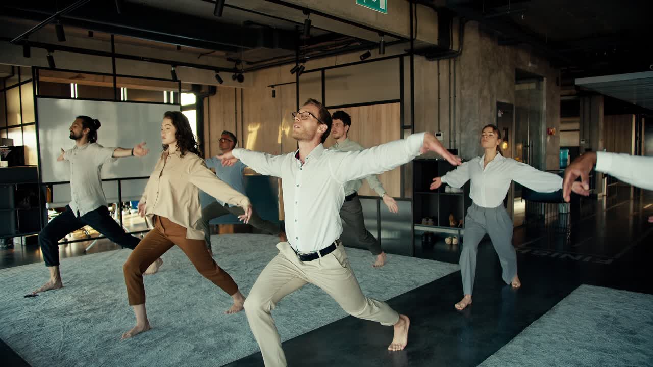 ⁇  셔츠 와 안경 을 입은 한 사람 이 사무실 에서 동료 들 과 함께 요가 를 하고 있다