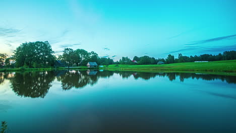 Timelapse-De-Una-Puesta-De-Sol-En-Un-Paisaje-Rural-Con-Un-Lago-Y-Un-Cielo-Azul