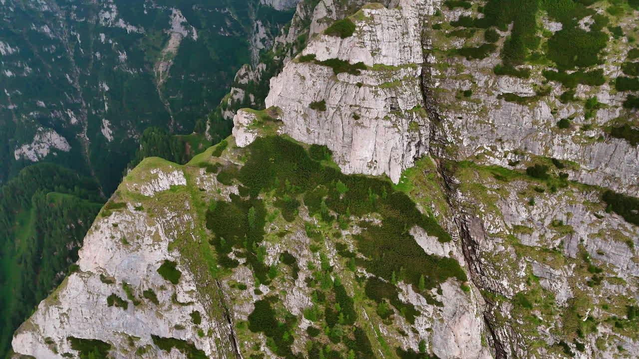 Flight around the stunning grey cliffs in the Southern Carpathians, Romania. Some greenery grows on the mountains slopes