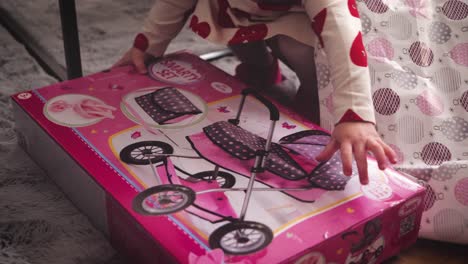 pequeño niño niño desempaquetando regalo de navidad, cochecito de juguete de muñeca