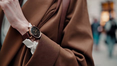 close-up detail of a person wearing a stylish watch with a brown coat
