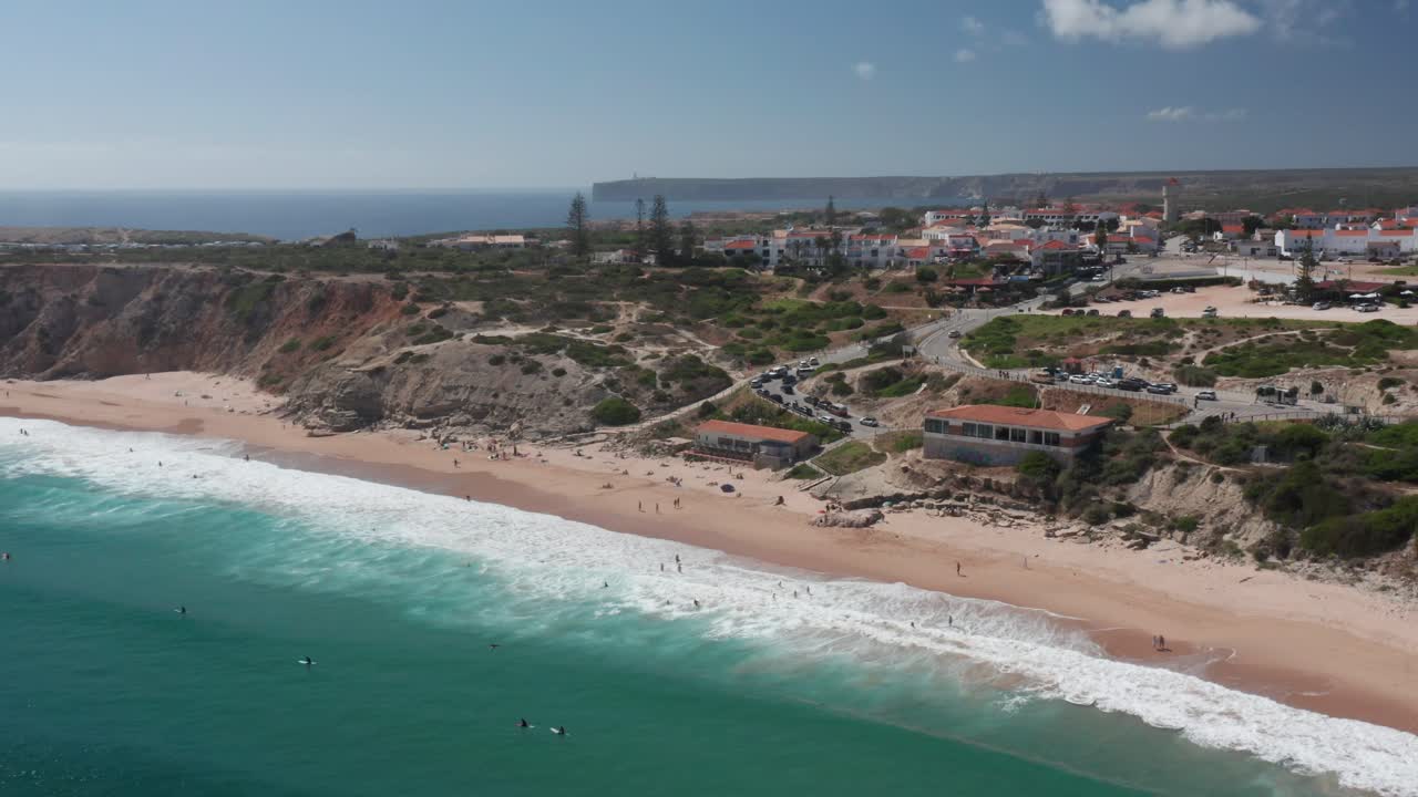 Clip drone di una spiaggia dell'Algarve d'estate con surfisti e cielo azzurro
