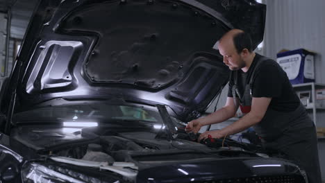 mecánico masculino utiliza una tableta con un software de diagnóstico de realidad aumentada. especialista inspeccionando el coche con el fin de encontrar componentes rotos dentro del compartimento del motor. servicio de automóviles moderno.
