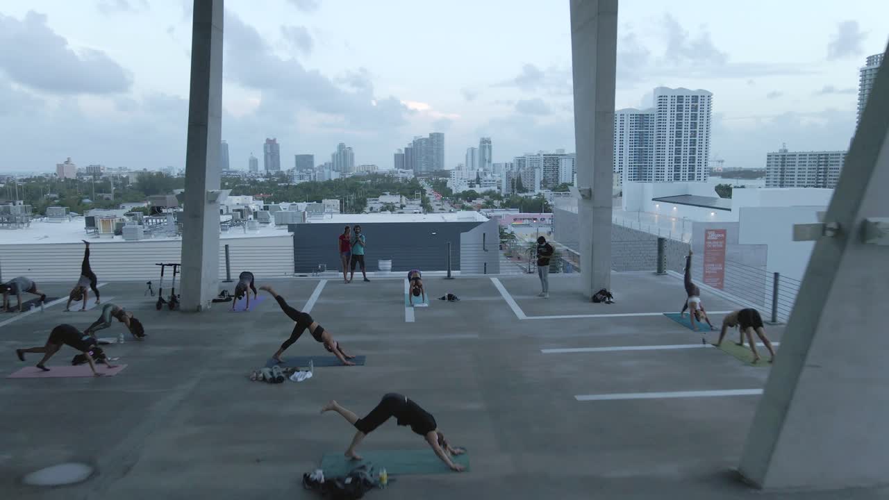Downward dog yoga pose in class held on open parkade level, aerial