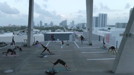 downward dog yoga pose in class held on open parkade level, aerial