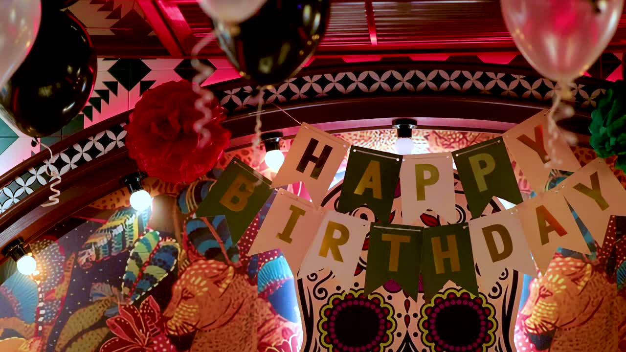 Vibrant birthday banner, balloons, and festive decor in warmly lit Mexican restaurant, slight camera movement
