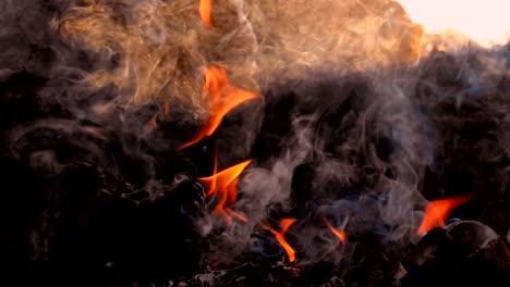 fuego en cámara lenta quemando bolsa de basura al amanecer fondo oscuro. humo blanco flotando a la contaminación del aire y el entorno peligroso. la basura es desecho de la comunidad. hace efecto invernadero de la tierra.