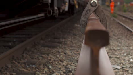 primer plano de una palanca de cambio de tren en las vías con trabajadores borrosos en el fondo