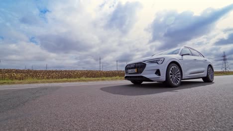 white luxury car on road on the field background. very fast driving of audi car on highway under beautiful sky at daylight.