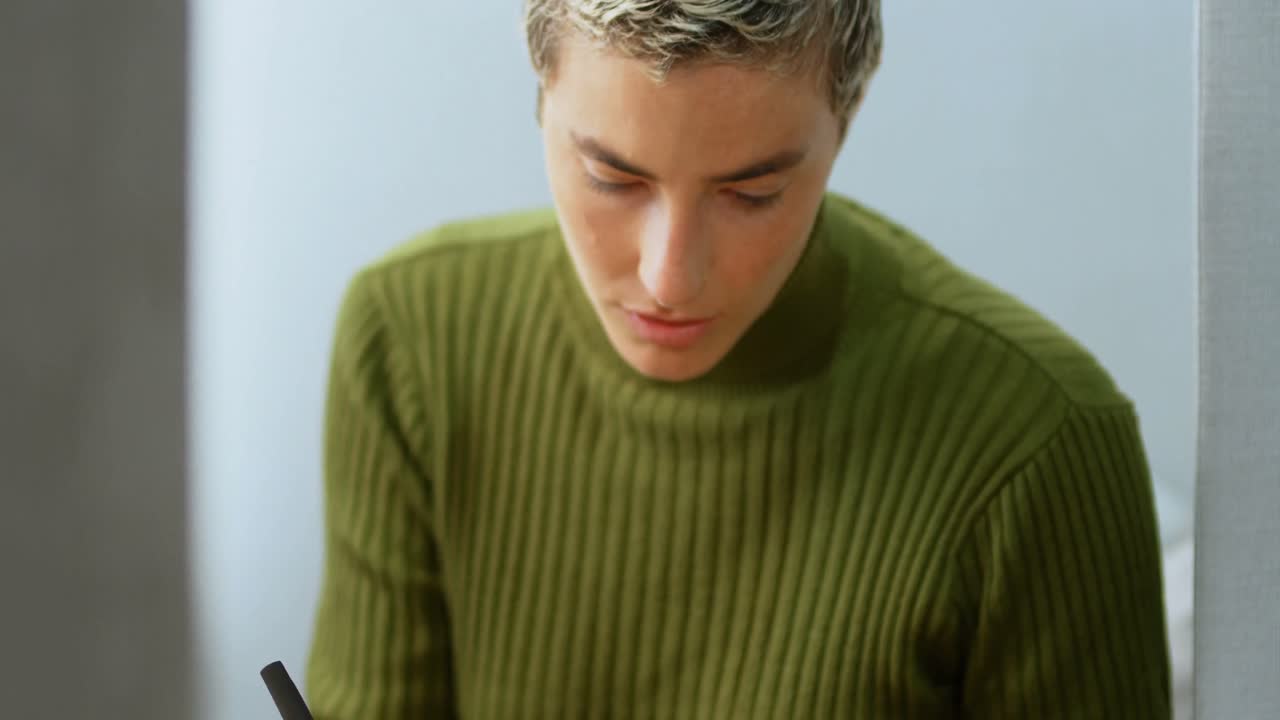 Female executive using mobile phone while writing on diary 4k