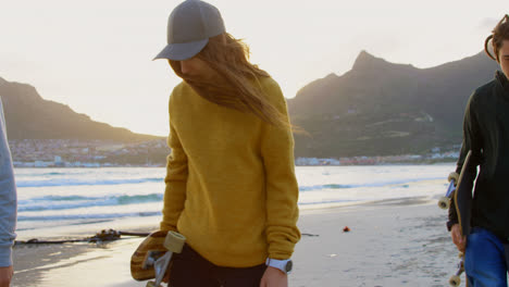 seitensicht junger kaukasischer freunde, die beim sonnenuntergang zusammen am strand spazieren gehen 4k