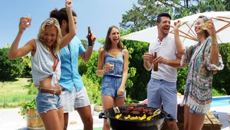 group of friends dancing and having drinks while preparing barbeque