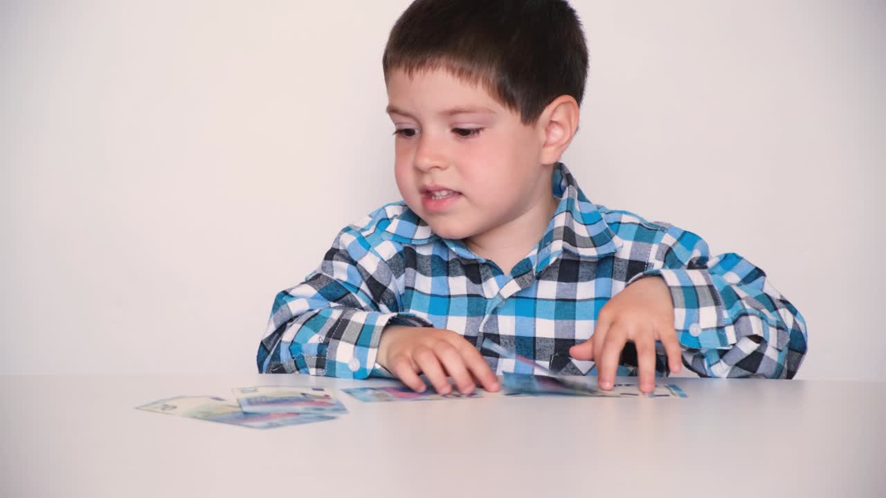 4 살짜리 소년은 돈을 세고 손에 유로를 들고 있습니다.