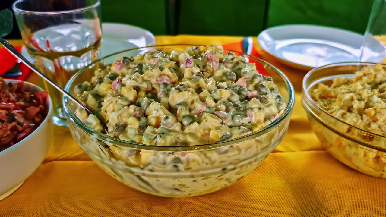 Traditional slavic rosol vegetable salad in glass bowl served on yellow tablecloth outdoors