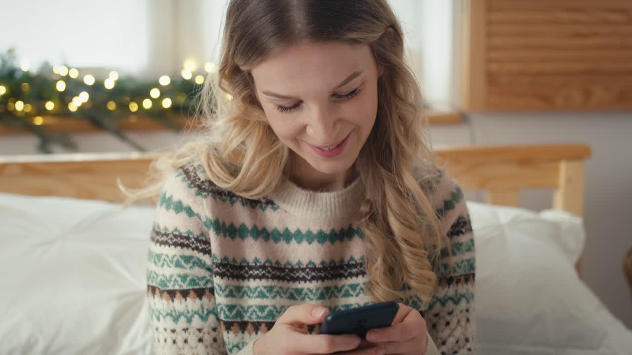 Donna caucasica che usa lo smartphone mentre è seduta nel periodo natalizio.