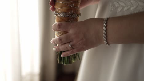 bride holding a bouquet, showcasing her engagement ring and bracelet, ready for the ceremony